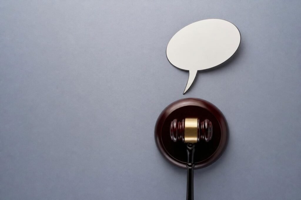Martillo de juez con un globo de diálogo vacío sobre fondo gris.